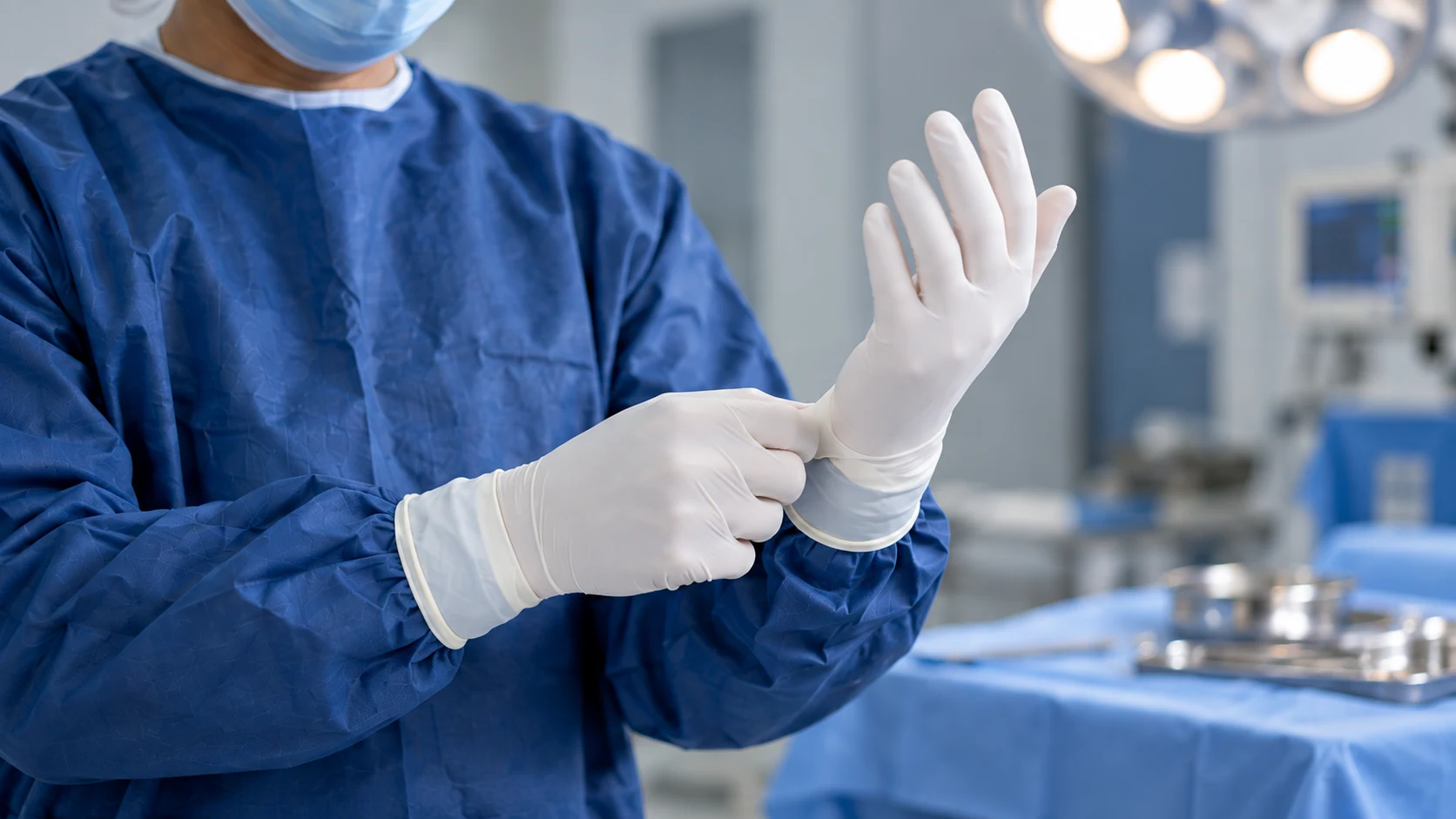 Illustrative surgical preparation: a clinician putting on sterile gloves